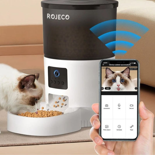 Distributeur de croquettes pour chat connecté, chat mangeant tandis qu’un smartphone affiche l’application de contrôle à distance.